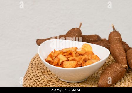 Copeaux de manioc ou de manioc bio dans un bol et un tubercule de tapioca. En-cas épicés chauds et populaires en Indonésie. Gros plan. Banque D'Images