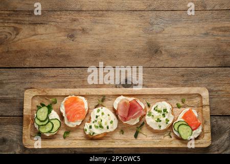 Délicieux sandwiches avec fromage à la crème et autres ingrédients sur une table en bois, vue sur le dessus. Espace pour le texte Banque D'Images