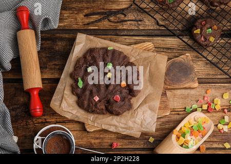Biscuits au chocolat non cuits avec fruits confits sur une table en bois, plat Banque D'Images