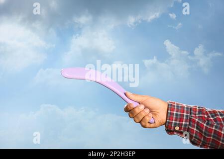 Homme lançant boomerang contre le ciel bleu, gros plan Banque D'Images
