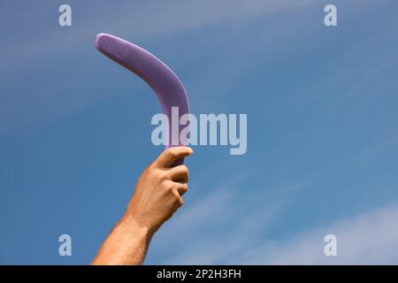 Homme lançant boomerang contre le ciel bleu, gros plan. Espace pour le texte Banque D'Images