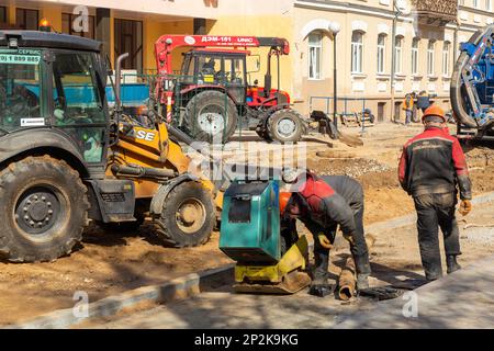 Grodno, Bélarus - 06 mars 2022: Des travailleurs avec l'aide d'équipements de terrassement reconstruisent des services publics souterrains dans l'une des rues les plus anciennes Banque D'Images