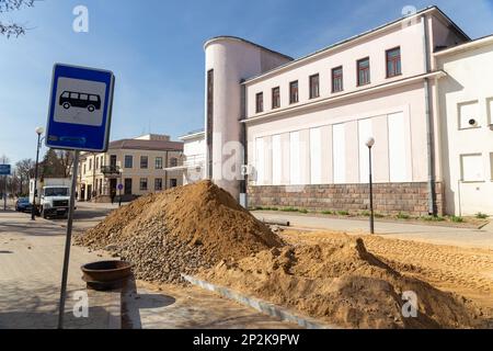 Grodno, Bélarus - 06 mars 2022: Des travailleurs avec l'aide d'équipements de terrassement reconstruisent des services publics souterrains dans l'une des rues les plus anciennes Banque D'Images