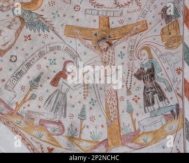 Homme riche et pauvre s'agenouillant devant Jésus sur la croix, un ancien mur-peinture dans l'église de Keldby, Danemark, 10 octobre 2022 Banque D'Images