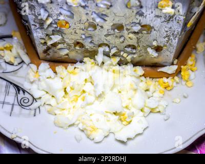 Protéines d'œuf râpées. produit protéique. Préparation de salade. Œuf dur râpé sur une planche à cuisine. Banque D'Images