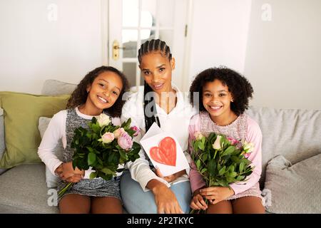 Maman et filles africaines tenant des bouquets célébrant les vacances à la maison Banque D'Images