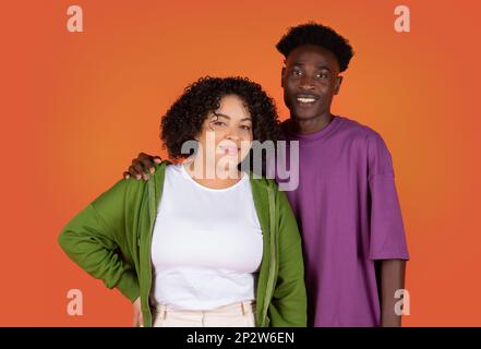Portrait d'un beau couple de course mixte, enveloppant, souriant à l'appareil photo Banque D'Images