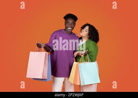 Un jeune couple multiracial heureux tenant des sacs d'achats Banque D'Images