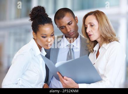 Les gens d'affaires qui passent par des documents. Portrait de personnes d'affaires multiraciales passant par des documents au bureau. Banque D'Images