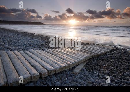 Des rayons de crépuscule émergent de derrière les nuages au-dessus de la côte au coucher du soleil, Westward Ho!, North Devon, Angleterre, Royaume-Uni Banque D'Images