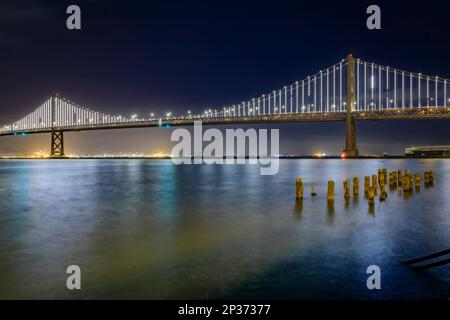 Le pont de la baie de San Francisco s'allume la nuit, reflétant l'eau dans la baie, exposition longue. Les feux s'éteignent sur le 5 mars 2023 Banque D'Images