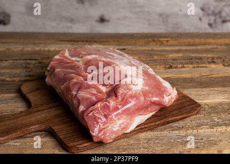 Morceau de filet de porc sur une planche à découper, sur une ancienne table en bois. Banque D'Images