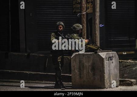 Naplouse, Palestine. 04th mars 2023. Deux soldats israéliens se tiennent sur la garde à côté d'un point militaire tandis que les forces armées israéliennes se déploient dans la ville de Hawara et ses environs après que les colons juifs extrémistes aient demandé une attaque sur la ville de Hawara, au sud de la ville de Naplouse, en Cisjordanie occupée. Crédit : SOPA Images Limited/Alamy Live News Banque D'Images