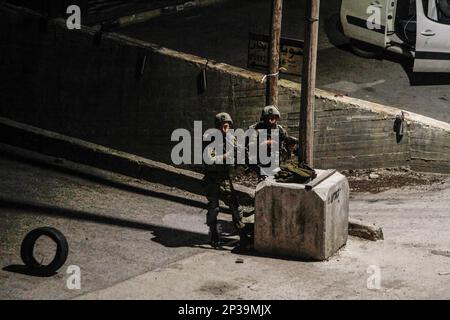 Naplouse, Palestine. 04th mars 2023. Deux soldats israéliens se tiennent sur la garde à côté d'un point militaire tandis que les forces armées israéliennes se déploient dans la ville de Hawara et ses environs après que les colons juifs extrémistes aient demandé une attaque sur la ville de Hawara, au sud de la ville de Naplouse, en Cisjordanie occupée. Crédit : SOPA Images Limited/Alamy Live News Banque D'Images