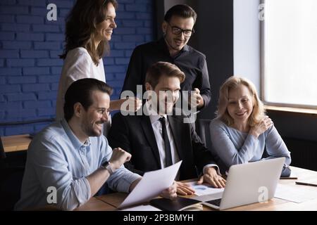 Joyeux groupe de collègues professionnels se réunissant sur un ordinateur portable Banque D'Images