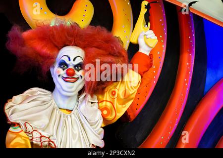 Une poupée de clown souriante regarde dans la caméra avec un pistolet soulevé dans sa main. Photo de haute qualité Banque D'Images