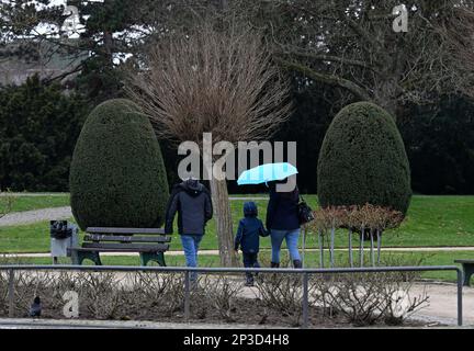 05 mars 2023, Rhénanie-du-Nord-Westphalie, Königswinter : armé d'un parasol dans la Rheinaue. Les météorologues prévoient des températures froides avec la pluie pour la semaine suivante. Le printemps est encore loin. Photo: Roberto Pfeil/dpa Banque D'Images