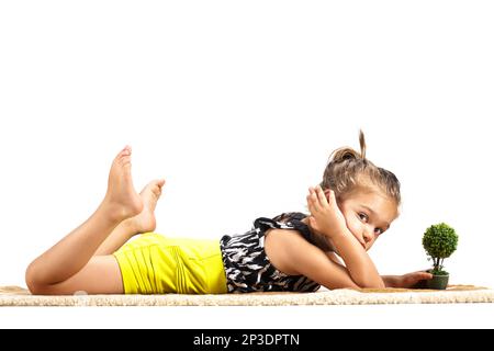 mignon litthe fille couché sur le sol et jouant avec petit petit arbre jouet Banque D'Images