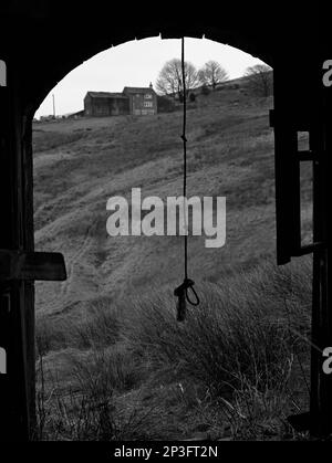 Une balançoire à corde est suspendue de façon inquiétante dans la grange abandonnée de Lower Intake Farm, Marsden, West Yorkshire Banque D'Images