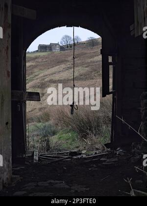 Une balançoire à corde est suspendue de façon inquiétante dans la grange abandonnée de Lower Intake Farm, Marsden, West Yorkshire Banque D'Images