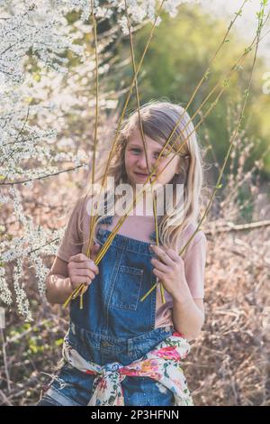 bonne fille avec de longs cheveux à côté de l'arbre floral de printemps en pleine floraison dans la nature de printemps Banque D'Images