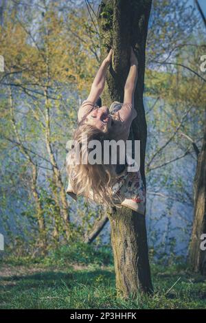 bonne fille grimpant l'arbre dans la nature de printemps vert vif Banque D'Images