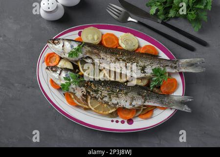 Mulet cuit avec des légumes, des épices et du citron servi sur une assiette, vue de dessus Banque D'Images