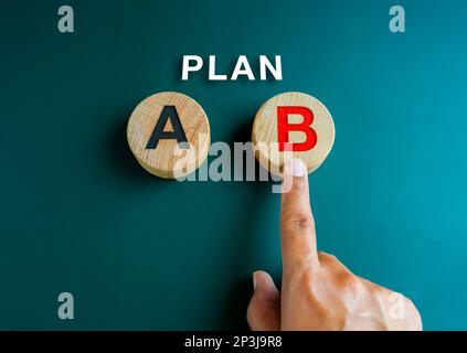 Plan B, concept de stratégie d'entreprise et de décisions. Plan, le texte sur la main qui choisit, le doigt pointant sur le plan B, l'alphabet rouge sur le bloc rond en bois Banque D'Images