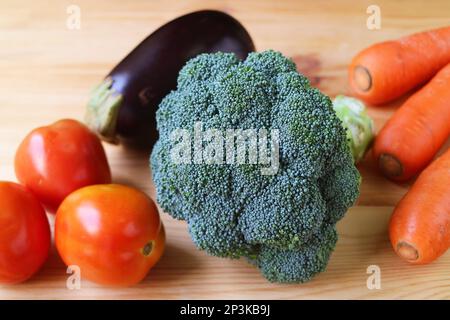 Gros plan de brocoli cru avec tomates, carottes et aubergines sur fond de bois Banque D'Images