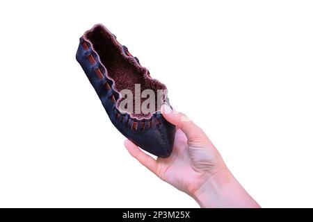 Femme tenant une chaussure rétro en cuir brut, isolée sur un fond blanc. Les chaussures sont de style vintage dans un matériau primitif. Banque D'Images