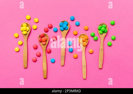 délicieuses sucreries douces colorées sur une cuillère sur fond coloré . Décoration de confiserie, vue de dessus avec espace pour les copies. Banque D'Images