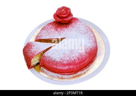 Gâteau rouge recouvert de massepain ou de mastic avec une pièce coupée et arrosé de sucre blanc en poudre, isolé sur fond blanc Banque D'Images