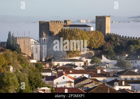 Vue sur la vieille ville et les murs avec le château d'Obidos dans la brume matinale, Obidos, région centrale, Portugal, Europe Banque D'Images