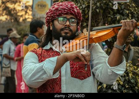 Kolkata, Inde - 12 février 2023: Un jeune musicien masculin jouant un violon dans une rue animée de la ville. Mise au point sélective. Banque D'Images