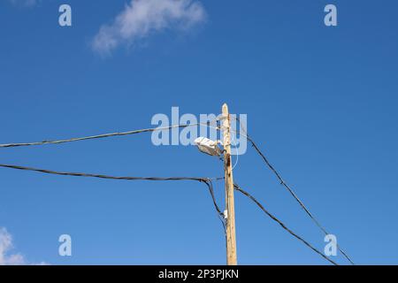 Poteau traditionnel en bois pour une lumière plutôt moderne. Câbles des deux côtés. Ciel bleu vif avec petits nuages blancs. Honduras, Fuerteventura, Canaries Banque D'Images