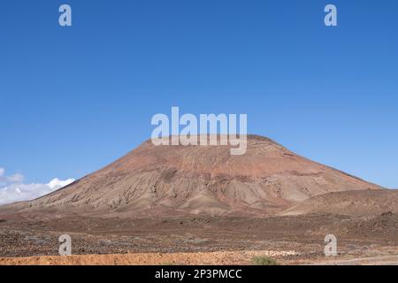 Impressionnant Red Mountail (Montana Roja), entouré par le désert. Ciel bleu vif en hiver avec quelques nuages blancs au pied de la montagne. Corralejo, Banque D'Images