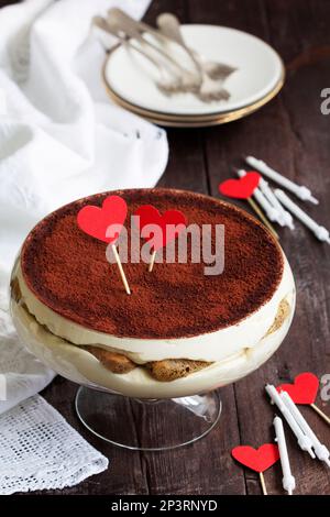 Tiramisu traditionnel italien servi dans un vase en verre décoré de coeurs en papier. Banque D'Images