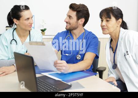 trois membres du personnel médical se sont assis autour d'un bureau de conférence Banque D'Images