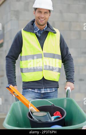 travailleur de la construction transportant des outils dans une brouette Banque D'Images