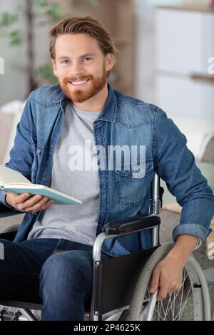 homme handicapé en fauteuil roulant avec un livre Banque D'Images