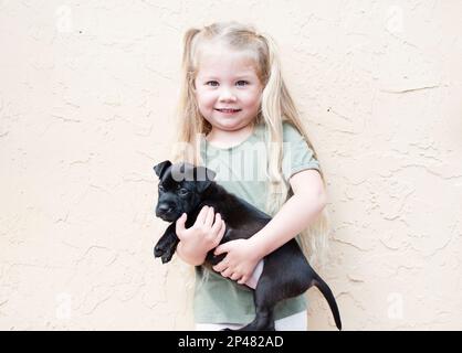 Bonne petite fille du Caucase avec un chiot. Chien de garde d'enfant. Concept PET. Enfant souriant Banque D'Images