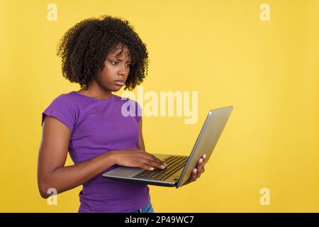 Femme inquiète avec des cheveux afro à l'aide d'un ordinateur portable Banque D'Images