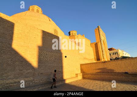 Des garçons ouzbèkes jouant au football par la mosquée de Kalan dans la vieille ville de Boukhara, Ouzbékistan. Banque D'Images