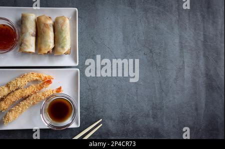 Rouleaux de printemps, sauce aigre-douce, tempura aux crevettes et soja sur fond rustique maquette avec vue de dessus. espace pour le texte Banque D'Images