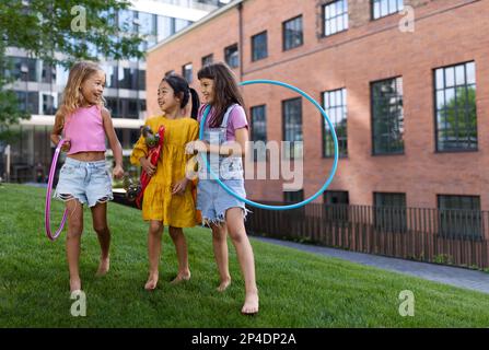 Des enfants heureux jouant et parlant ensemble dans le parc de la ville, pendant la journée d'été. Banque D'Images