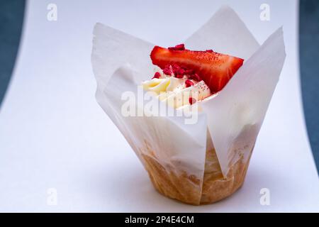 Cupcakes à la crème faits maison avec des fraises fraîches et une couche éponge de gâteau à la fraise dans un verre sur fond gris. Banque D'Images