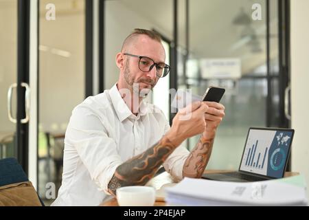 Souriant homme caucasien tenant crédit cad et téléphone mobile, en entrant des données pour le formulaire de site Web Banque D'Images