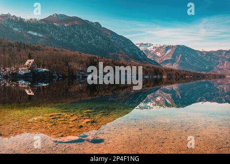 Vue panoramique sur le lac Bohinj, grand plan d'eau glaciaire dans le parc national slovène Triglav dans le froid février matin avec des montagnes reflétant Banque D'Images