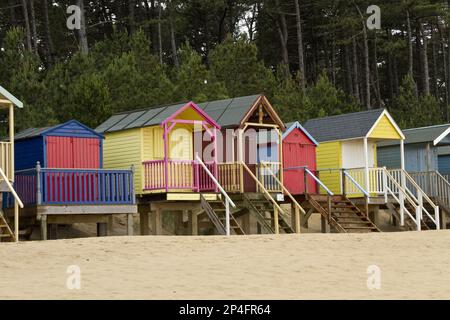 Cabanes de plage peintes en couleurs à Holkham Bay près de Wells by the Sea, North Norfolk, Angleterre. La plage de sable et les cabanes de cartes postales sont des vacances populaires Banque D'Images