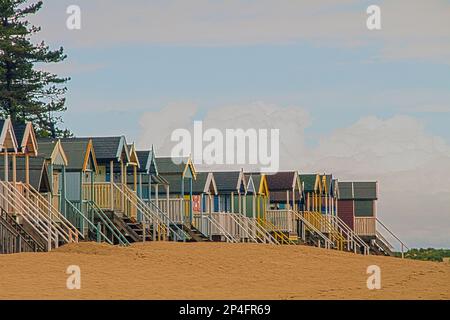 Cabanes de plage peintes en couleurs à Holkham Bay près de Wells by the Sea, North Norfolk, Angleterre. La plage de sable et les cabanes de cartes postales sont des vacances populaires Banque D'Images